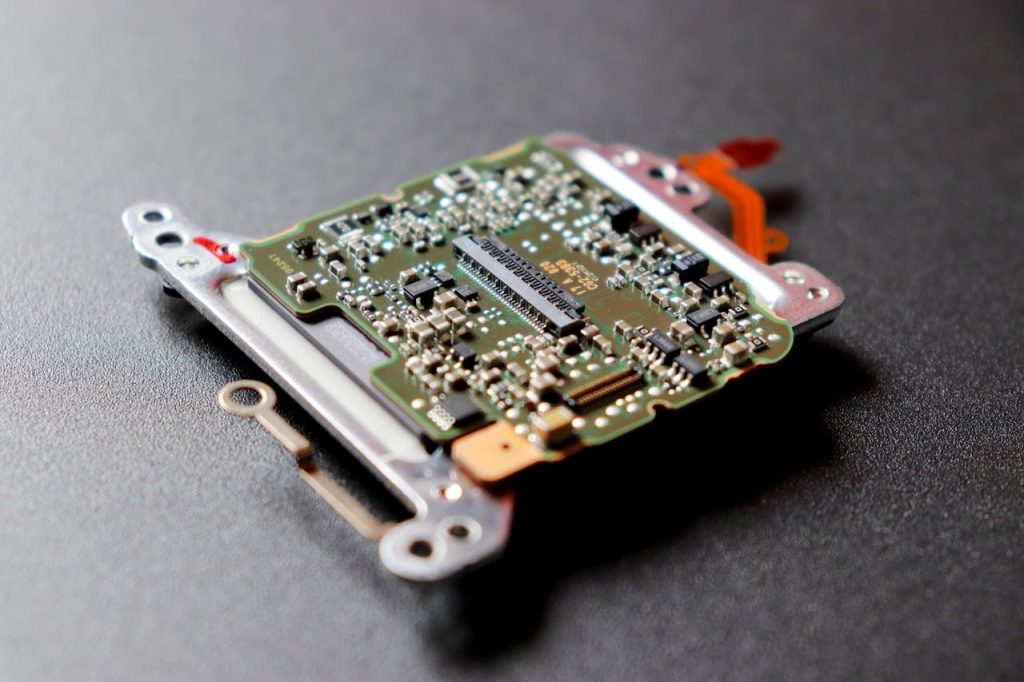 Detailed view of a microchip, showcasing intricate electronic components on a dark textured surface.